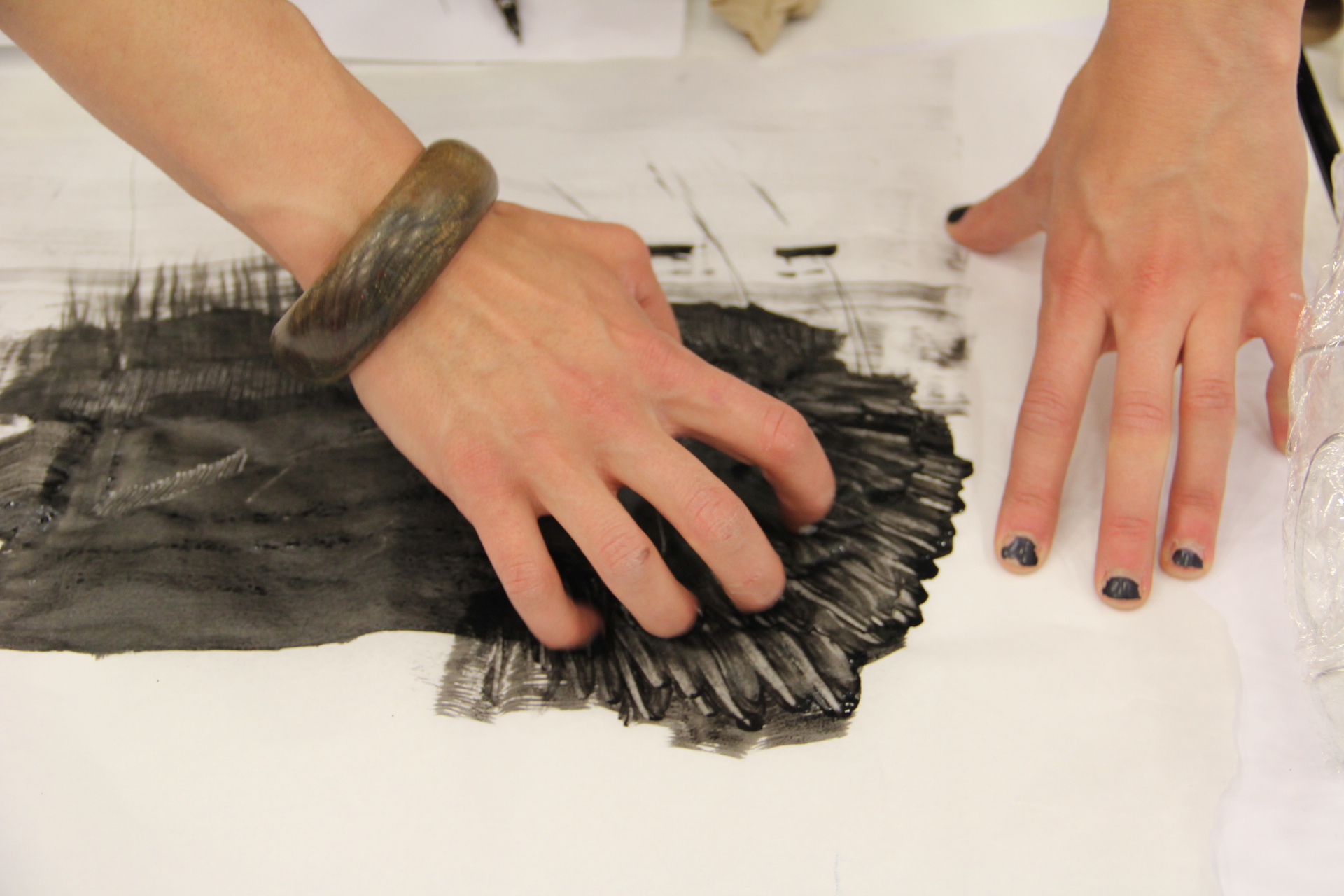 Hands rubbing charcoal into paper
