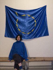 Artist Anastasia Eggers in her studio in front of a flag artwork